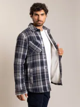 Camisa tipo campera de franela con estampado a cuadros en tonos azul, gris y blanco. Cuenta con forro interior de sherpa, cierre frontal con botones, cuello clásico y bolsillo en el pecho.