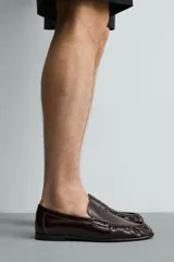 Mocasín de vestir negro de estilo clásico con detalle de antifaz en la parte superior, suela a tono y ligero tacón.