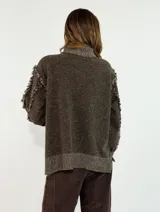 Sweater de punto color azul marino con cuello alto, diseño de rombos en relieve y detalles de flecos en las costuras de las mangas. Presenta un corte holgado con aberturas laterales en el ruedo.