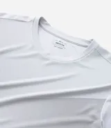 Remera deportiva de hombre, color gris claro, con cuello redondo y manga corta. Presenta un sutil efecto degradado o panel de color más claro en la zona del pecho.