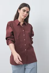 Camisa de manga larga de algodón en color blanco, con cuello clásico, cierre frontal de botones y silueta relajada.