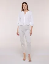 Pantalón color beige de corte entallado y largo cropped, confeccionado en tejido de punto con elasticidad técnica. Cuenta con pretina ancha y plana, bolsillos simulados al frente y bolsillos tipo ojal en la parte posterior.