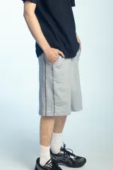 Bermuda deportiva de felpa color negro, de corte ancho y largo por debajo de las rodillas, con cintura elástica.
