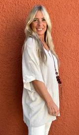 Blusa de corte holgado y diseño minimalista, confeccionada en tela texturizada color beige, con escote en V y mangas cortas tipo kimono.