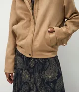 Campera tipo bomber de tacto gamuzado, con cuello alto, cierre frontal con botones a presión, bolsillos laterales y puños ajustables con botón.