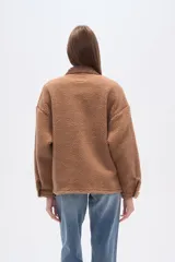 Campera tipo shacket de corderito color crema, con detalles en pana marrón en cuello, solapa de botones y bolsillos frontales. Diseño holgado de manga larga con cierre frontal de botones.