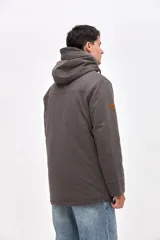 Campera tipo parka de gabardina color beige, con capucha ajustable, cierre frontal y bolsillos laterales con solapa. Presenta un diseño clásico con interior capitoneado.