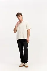 Camisa de manga corta color beige con tejido calado de líneas verticales y cuello abierto estilo resort.