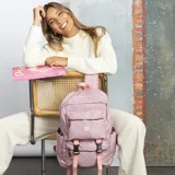 Mochila de gran capacidad en color rosado, confeccionada en nylon. Cuenta con un compartimento principal con cierre, un bolsillo frontal con cierre, dos bolsillos laterales abiertos y correas ajustables con hebillas de seguridad. Incluye correas de hombro y espalda acolchadas para mayor comodidad.