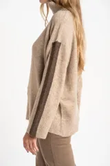 Polera oversize color beige melange, de punto con mangas largas y detalles de franjas marrones en las mangas y cuello.