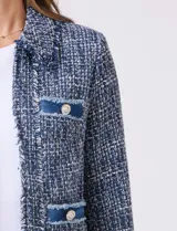 Chaqueta de tweed azul con cuello a la base, abertura central y bolsillos delanteros. Presenta detalles de denim en los bolsillos y puños, con botones perlados. Terminación desflecada y forro interno.