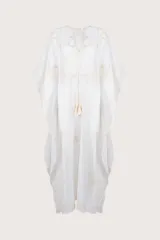 Kaftán largo de algodón traslúcido color blanco marfil, con bordados en tono beige claro en el frente y en los bordes. Presenta un escote en V con cordones terminados en borlas.
