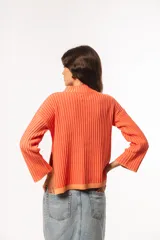 Sweater de punto acanalado color coral, con cuello alto y mangas largas con puños acampanados.