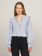 Blusa celeste a rayas verticales, de corte amplio, con cuello mao, cierre de botones y volantes en los hombros.