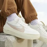 Championes Nike Air Force 1 Shadow, modelo de plataforma con diseño en capas. Presenta una base en tono crema con detalles en rosa pastel y celeste en los swooshes laterales. Suela de goma con tecnología Air para mayor amortiguación.