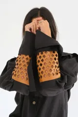 Camisa de lino color naranja, con mangas largas abuchonadas, cuello camisero y cierre frontal con botones. Presenta un diseño único con detalle calado en los puños.