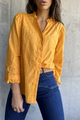 Camisa color mostaza con bordado de flores, cuello con volados, mangas largas abullonadas y cierre frontal con botones.