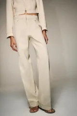 Pantalón de tiro alto con trabillas, bolsillos laterales y cierre frontal con cremallera y gancho metálico. Presenta un diseño de corte recto con costuras decorativas a contraste en la cintura y el ruedo.