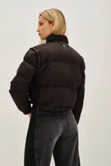 Campera puffer color tostado, con cierre frontal y botones a presión, cuello alto y puños tejidos acanalados.