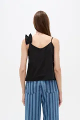 Musculosa de algodón color negro con escote en V profundo, tirantes finos y un volado diagonal fruncido que cruza desde el hombro izquierdo hasta el dobladillo.