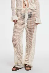 Pantalón blanco de tejido calado, con cintura elástica y cordón ajustable, de corte recto y holgado.