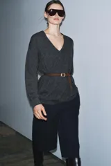Jersey oversize de lana con escote en pico y manga larga. Incluye un cinturón fino de cuero en tono marrón con hebilla metálica dorada.