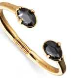 Pulsera rígida dorada de aleación de metales bañada en oro 18k, con dos cristales facetados grises en los extremos.