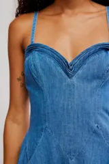 Vestido midi de denim azul, con silueta en línea A, escote corazón, tirantes finos y detalle de volados en el ruedo.