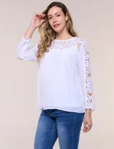Blusa blanca de gasa liviana con forro interno en el cuerpo, de estilo boho-chic y silueta semi holgada. Presenta escote redondo con canesú de encaje calado en el frente y mangas largas con paneles longitudinales de encaje.