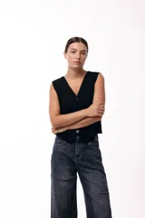 Chaleco tejido de punto con escote en V y cierre frontal de botones. Presenta una silueta recta y diseño sin mangas, ideal para un estilo sofisticado y versátil.