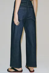 Jeans wide leg de tiro alto en color azul oscuro, con trabillas en la cintura, diseño de cinco bolsillos, nervios delanteros marcados y pespuntes a contraste. Cuenta con cierre frontal de cremallera y botón metálico.