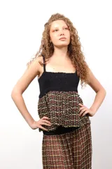 Top de diseño híbrido con parte superior tejida en crochet negro y base de tejido plano con estampado de cuadros en tonos tierra, amarillo y rojo. Presenta breteles finos y detalle de bordado en la espalda.