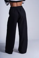 Pantalón de corte amplio y tiro alto, color beige, con elástico en la cintura trasera, pinzas frontales marcadas y bolsillos laterales.