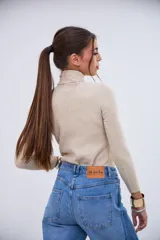 Polera de punto acanalado color beige, con cuello alto y mangas largas.