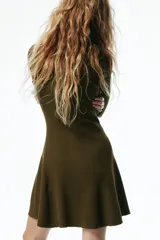 Vestido corto de punto acanalado color verde militar, con escote redondo, cierre frontal parcial con botones, manga larga, cuerpo entallado y falda evasé con vuelo.