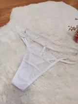 Tanga de microtul y encaje color blanco, con diseño de tiras regulables en la cintura y forro de algodón.
