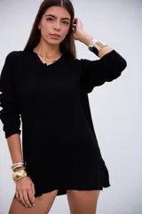 Sweater de punto acanalado color negro, con cuello en V y mangas largas. Presenta un diseño de corte holgado con aberturas laterales en el ruedo.