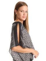 Blusa de gasa con estampado geométrico en tonos negro y gris. Presenta un diseño de mangas tipo dolman o japonesas, cuello recto y cintura elastizada con detalle de punto smock.