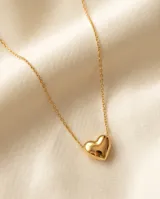 Collar de acero con baño de oro, compuesto por una cadena fina de eslabones y un dije central en forma de corazón liso y brillante.