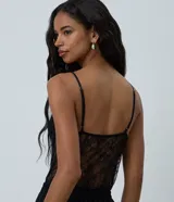 Body de encaje negro con transparencias, escote en V profundo y breteles finos ajustables. Cuenta con copas integradas y cierre inferior.