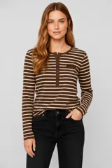 Remera de manga larga, cuello redondo con abertura de botones (tipo Henley) y un bolsillo pequeño en el pecho. Presenta un patrón de rayas horizontales anchas en tonos marrón oscuro y beige claro.