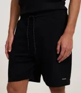 Bermuda masculina de algodón con felpa, color negro, corte slim fit. Presenta cintura elástica con cordón ajustable, bolsillos y etiqueta aplicada.