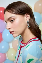 Caravanas largas colgantes con diseño de tres flores en metal plateado, cada una con una piedra verde brillante en el centro.