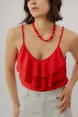 Musculosa negra con escote en V, breteles finos regulables y doble volado frontal con pespuntes.
