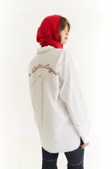 Camisa blanca de corte oversize con bordado en la espalda con la frase 'The Winter League', recortes con costuras a contratono y mangas largas.