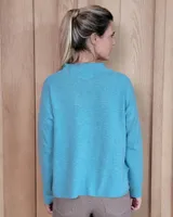 Sweater de tejido de punto color turquesa, con cuello en V y mangas largas de corte holgado.