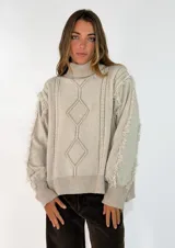 Sweater de punto color azul marino, con cuello alto, diseño de rombos en relieve y detalle de flecos en las mangas.