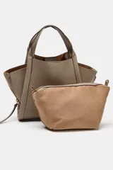 Bolso bandolera de formato city en color gris topo, con pespuntes decorativos, doble asa de mano, cremalleras laterales y cierre imantado.