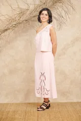 Conjunto negro de dos piezas de lino, compuesto por un top de un hombro con bordados florales y una falda midi con aberturas laterales y bordados florales.