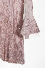 Mono corto de fiesta color rosado con lentejuelas, mangas largas acampanadas y escote redondo.